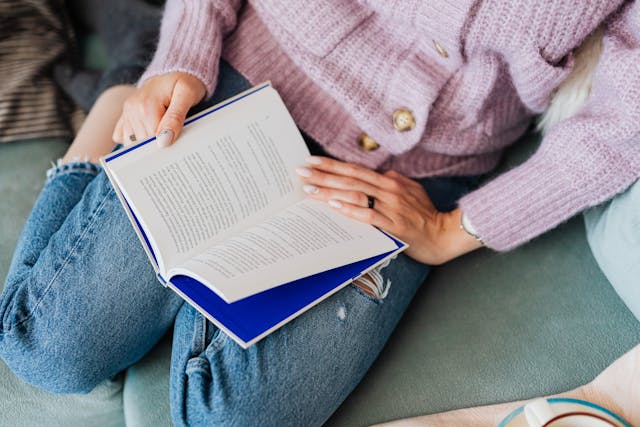 Close-up of a woman holding a blue book in her lap