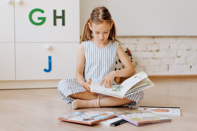A girl reading a book with alphabets behind her