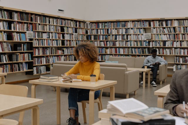 Person in a yellow shirt sitting at a table in a library