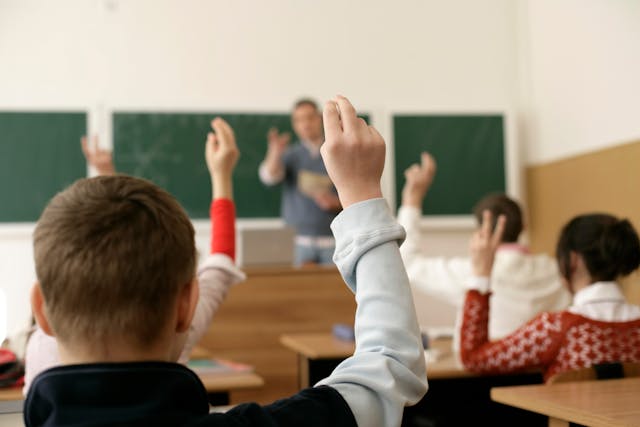 Close-up of a student raising their hand in a classroom