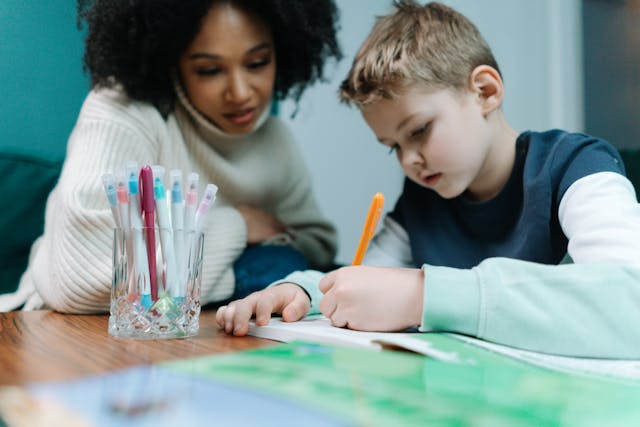 Woman and child studying together with colorful pens